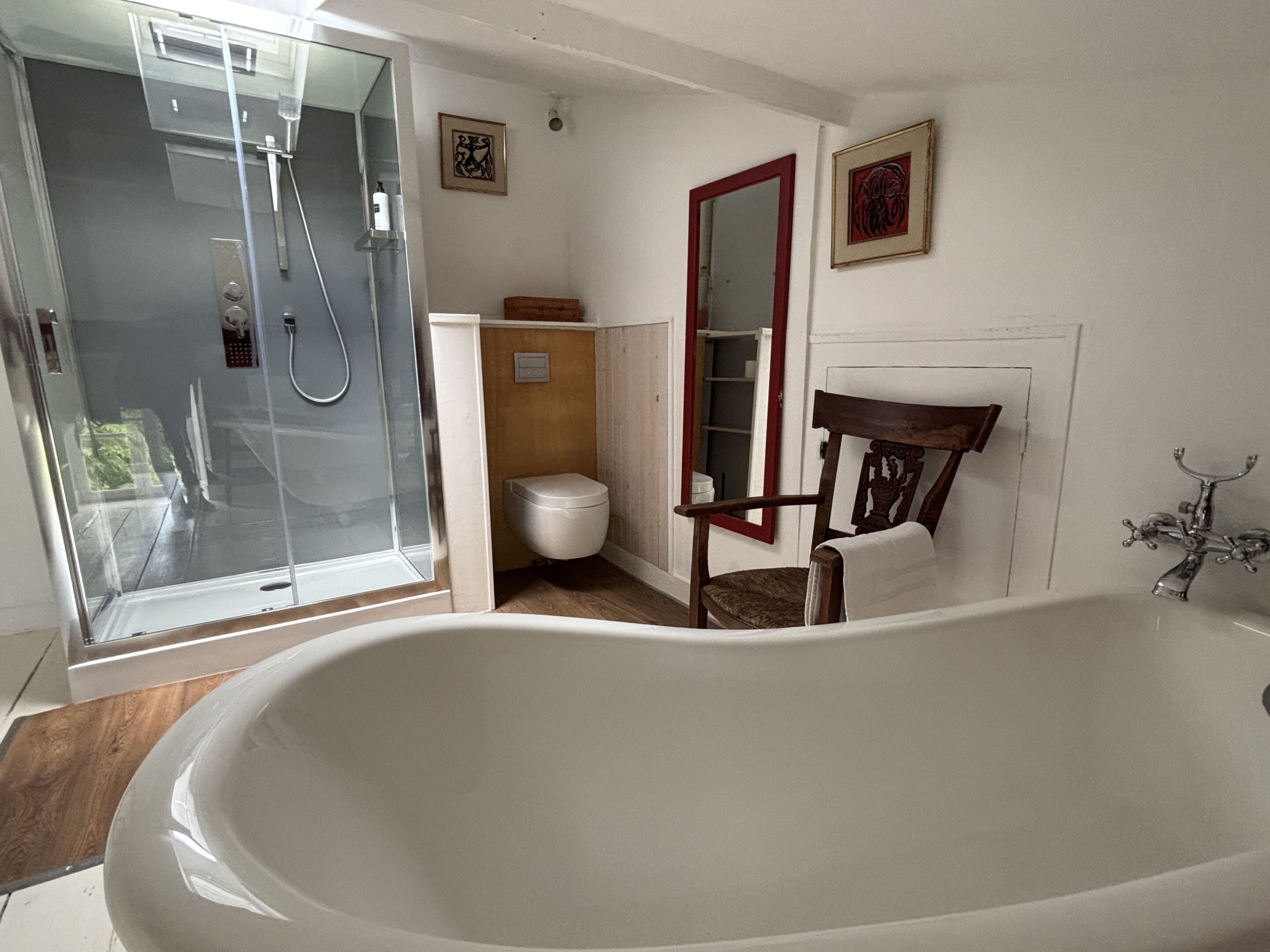 Een badkamer met een badkuip, douche, toilet en een stoel.