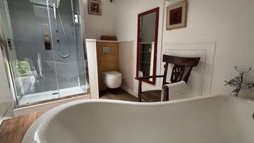 Een badkamer met een badkuip, douche, toilet en een stoel.
