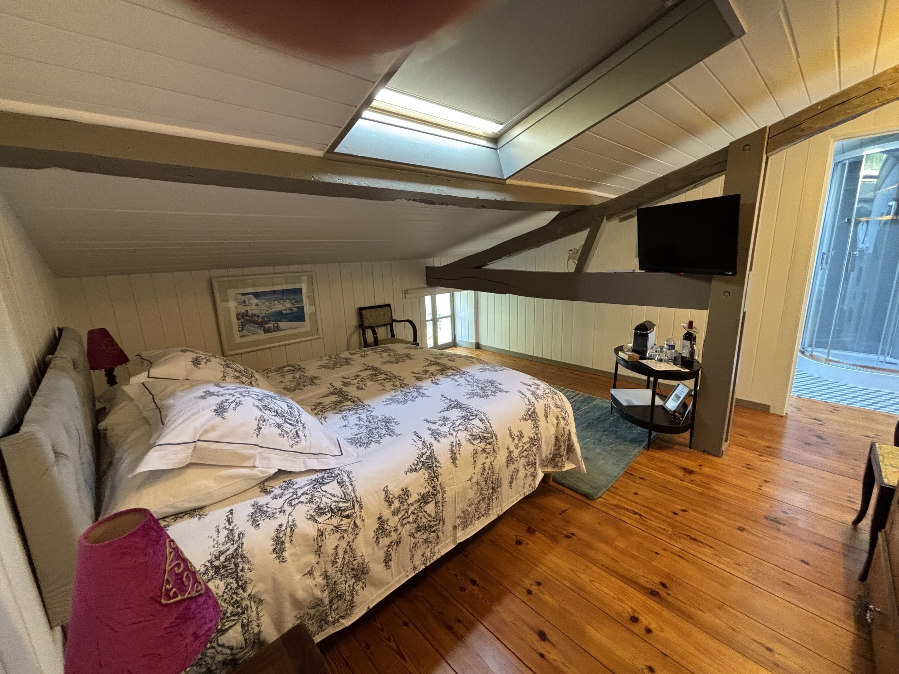 Une chambre à coucher avec un lit, un bureau, une chaise, une télévision et une fenêtre.