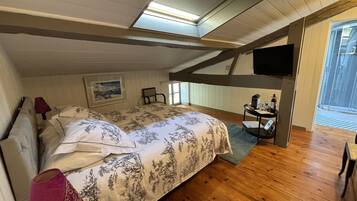 Une chambre à coucher avec un lit, un bureau, une chaise, une télévision et une fenêtre.