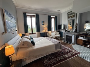 A hotel room with a bed, a desk, a television, and a fireplace. - Maison Jéroboam (Saint-Estephe)