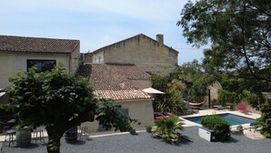 A courtyard with a swimming pool, outdoor seating, and a building with a tiled roof. - Maison Jéroboam (Saint-Estephe)