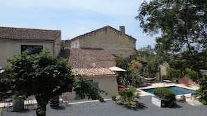 A courtyard with a swimming pool, outdoor seating, and a building with a tiled roof. - Maison Jéroboam (Saint-Estephe)