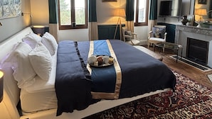 Habitación de hotel con una cama grande, televisión, chimenea y vistas al exterior.