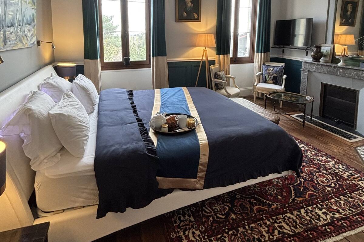 A hotel room with a large bed, a television, a fireplace, and a view of the outdoors.