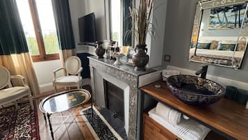 A room with a fireplace, a large mirror, a bowl sink, and a television.