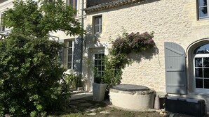 A stone building with a garden, a large tree, and a water feature. - Maison Jéroboam (Saint-Estephe)