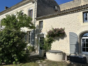 A stone building with a garden, a large tree, and a water feature. - Maison Jéroboam (Saint-Estephe)