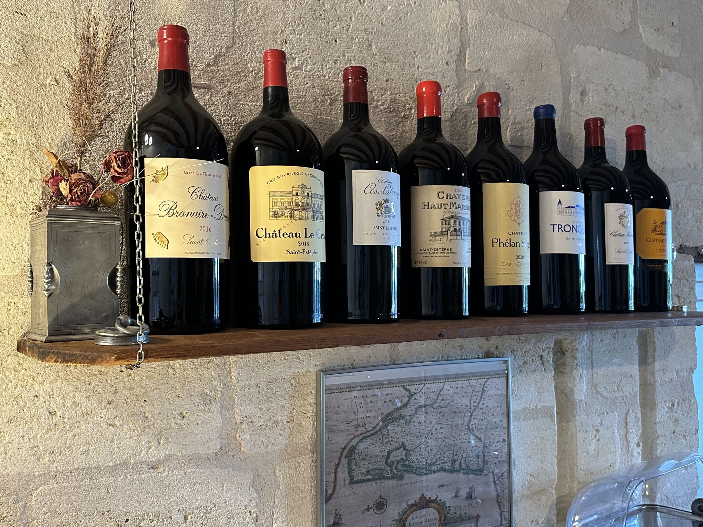 Reihe von Weinflaschen auf einem Regal vor einer strukturierten Wand.
