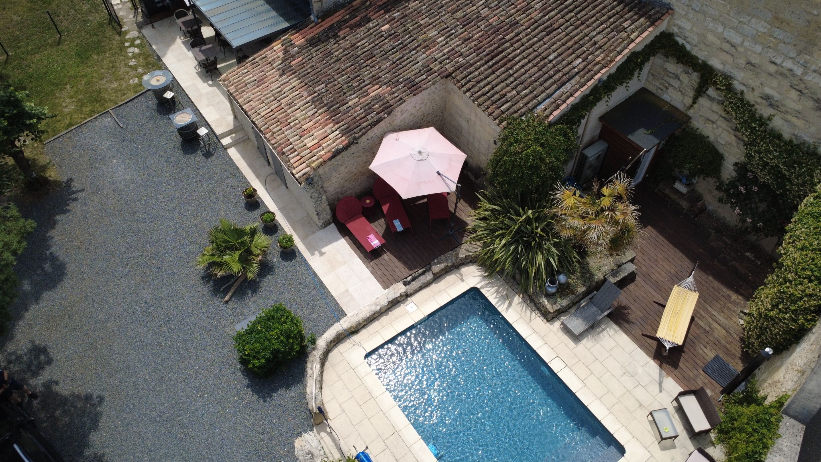 Vista aérea de un patio con piscina, mobiliario exterior y techo de tejas.