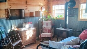 A rustic room with a bed, a desk, a chair, a dresser, and a window with a view.