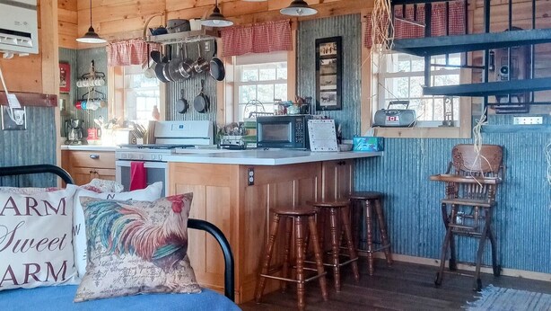 A cozy kitchen with wooden cabinets, a bar area, and a dining space with a blue tablecloth.