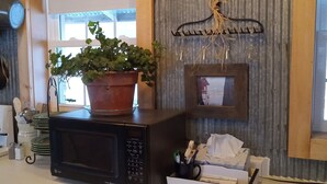 A kitchen with a microwave, a potted plant, a hanging light fixture, and a small window.