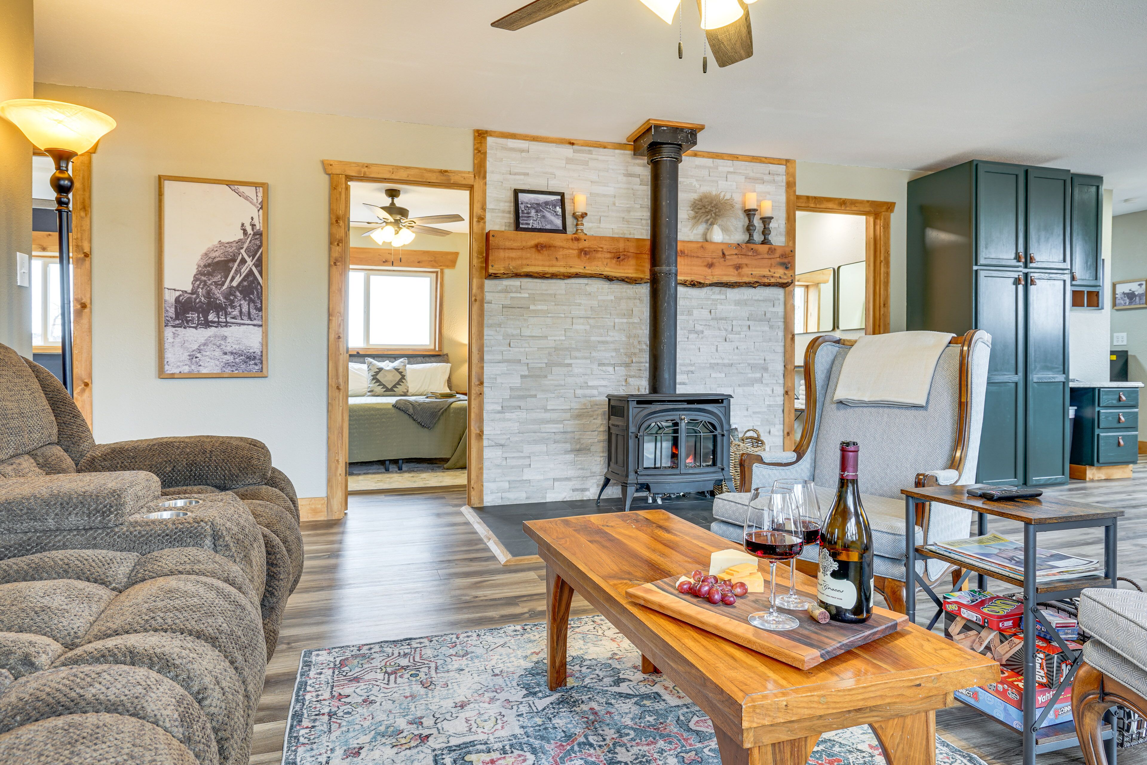 A cozy living room with a sofa, a wooden coffee table with wine glasses and cheese, a fireplace, and a green cabinet.