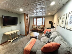 A living room with a sofa, armchairs, a coffee table, a TV, and a fireplace.