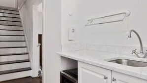 A modern kitchen with a stainless steel sink, a towel rack, and a staircase leading to another room. - Berkshire House Stay: 5BR/5BA (Lee)
