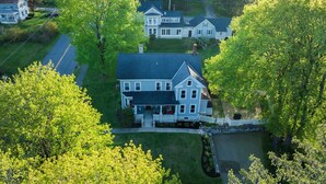 A large, two-story house with a prominent front porch, a driveway, and a small pond in the backyard. - Berkshire House Stay: 5BR/5BA (Lee)