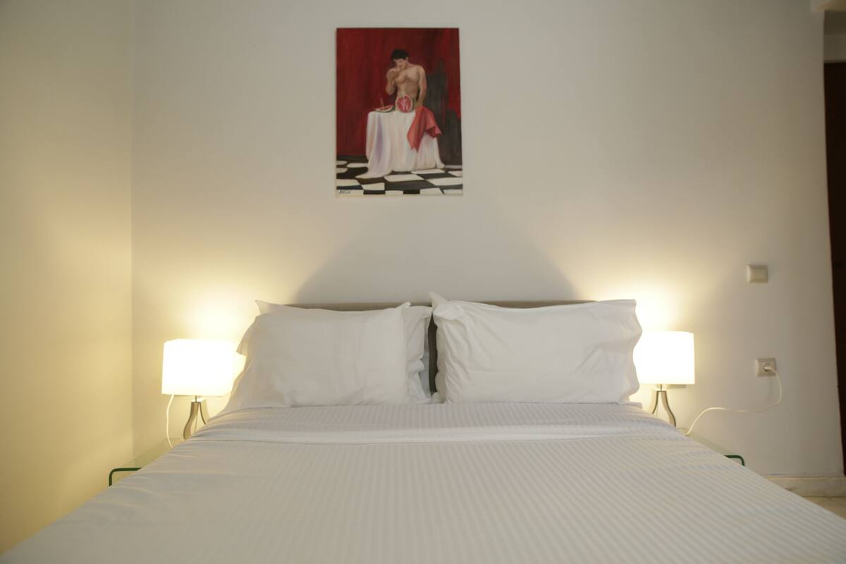 Une chambre d’hôtel avec un lit, deux lampes de chevet et un tableau au mur.
