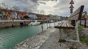 En havnefront med en bænk, en smal kanal og bygninger langs vandet.