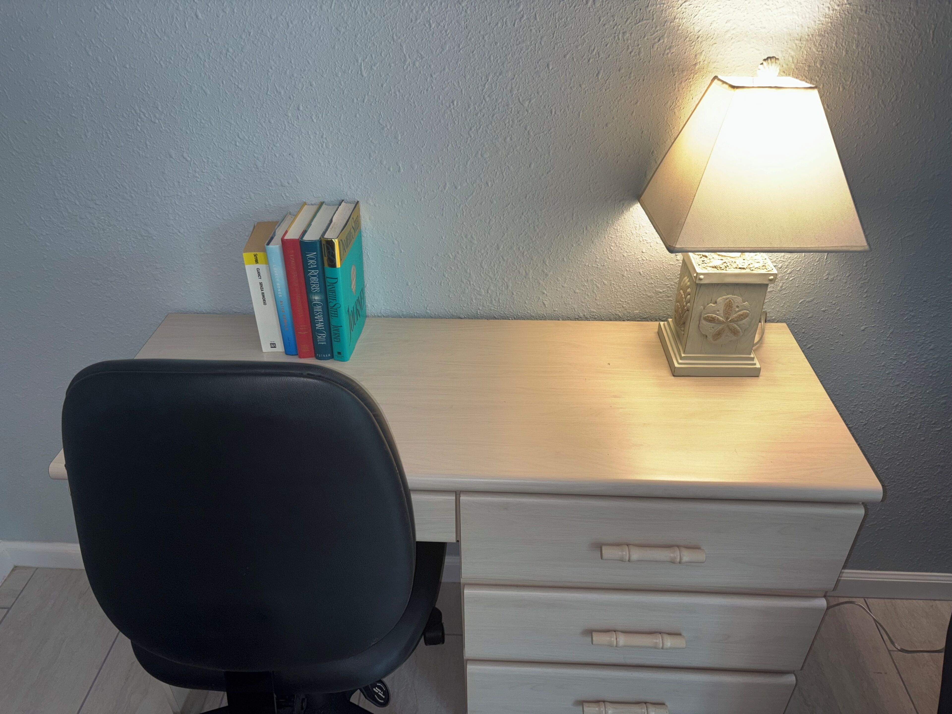 Un bureau avec une lampe, une chaise et plusieurs livres.