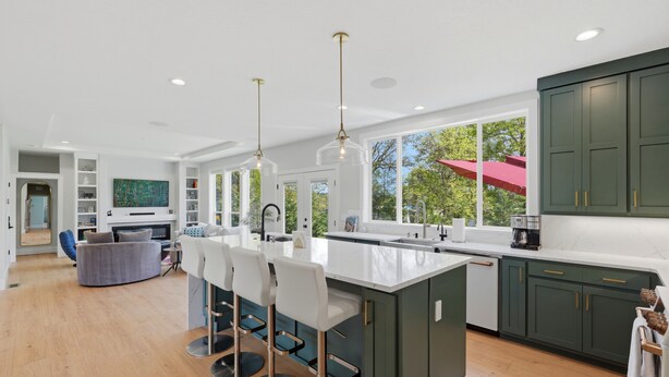 A modern kitchen with a large island, bar stools, and a view of the outdoors. - Luxury 3 King Suite Retreat 3 Blocks to Downtown! (Carlton)