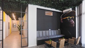Un interior modern amb un sofà gris, un paviment amb dibuixos en blanc i negre, i un mural gran a la paret.