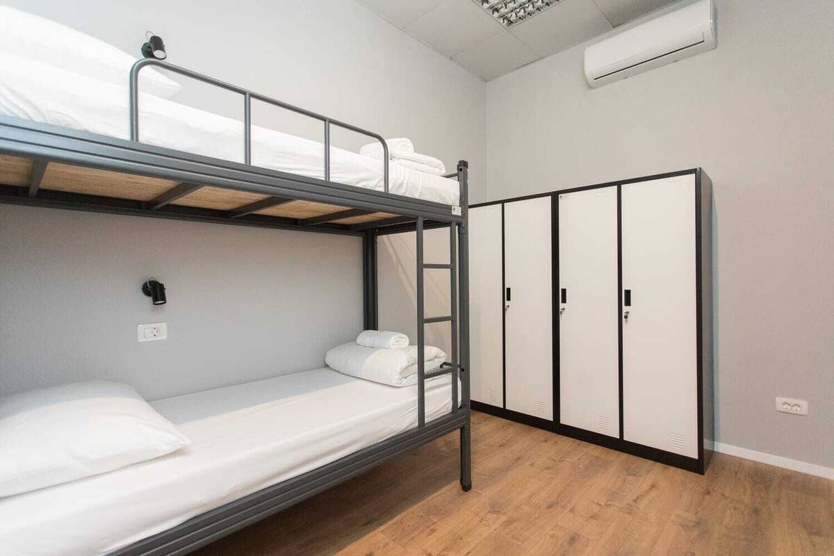 A bunk bed room with a wardrobe and a wall-mounted air conditioner.