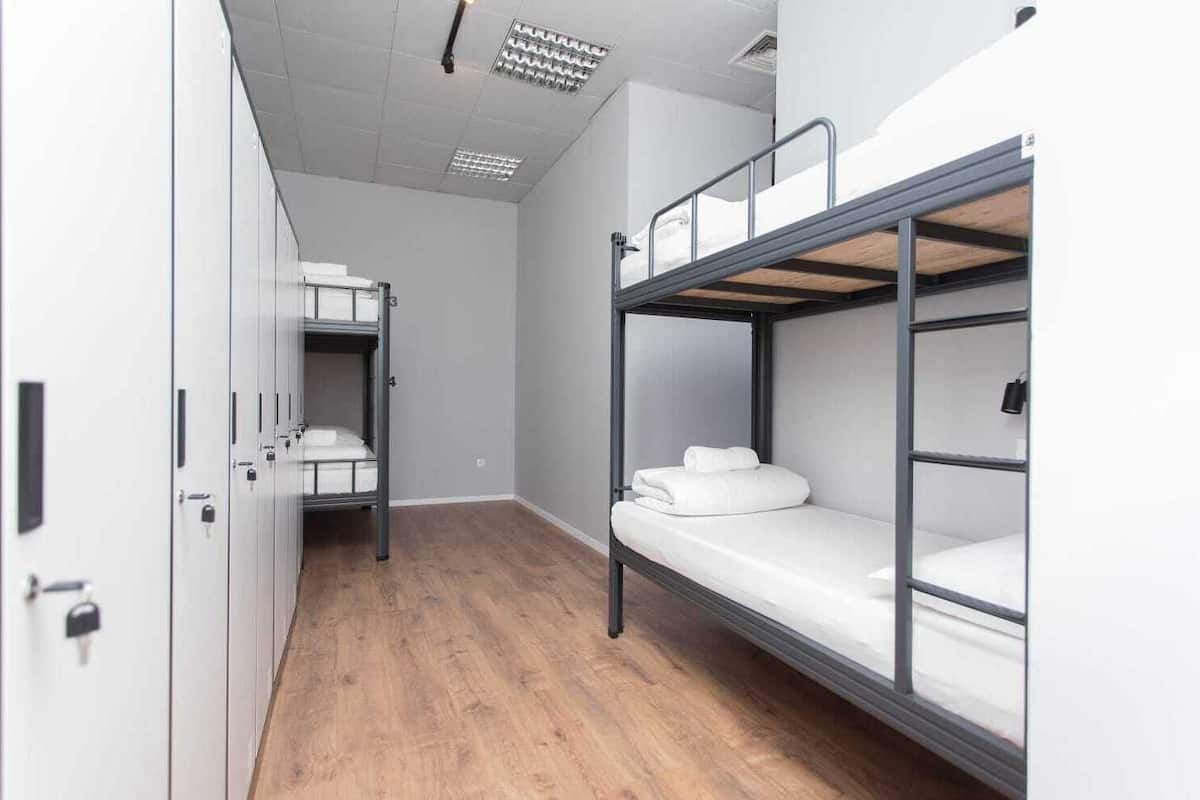 A dormitory room with bunk beds, a wardrobe, and a wooden floor.