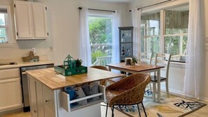 Una cocina compacta con encimera de madera, unidad de almacenamiento integrada y zona de comedor con mesa y sillas.
