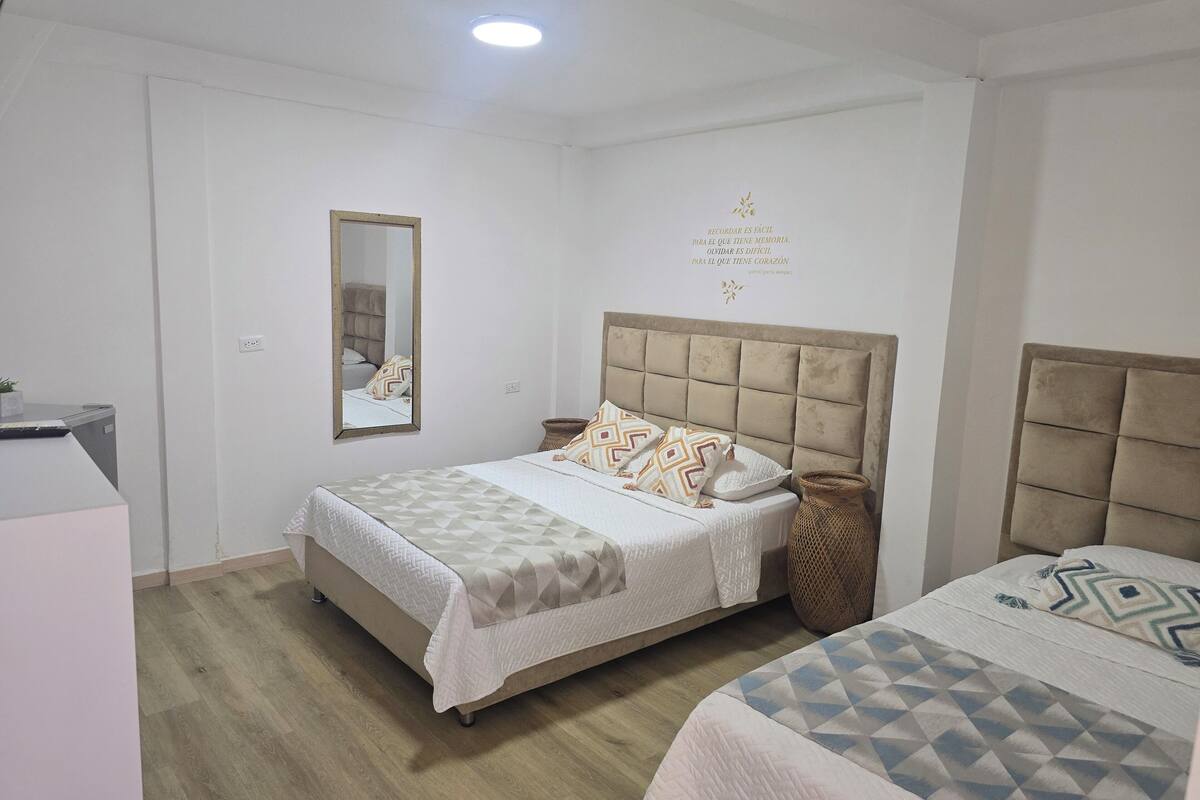 A bedroom with a bed, a mirror, and a wall with a decorative text.