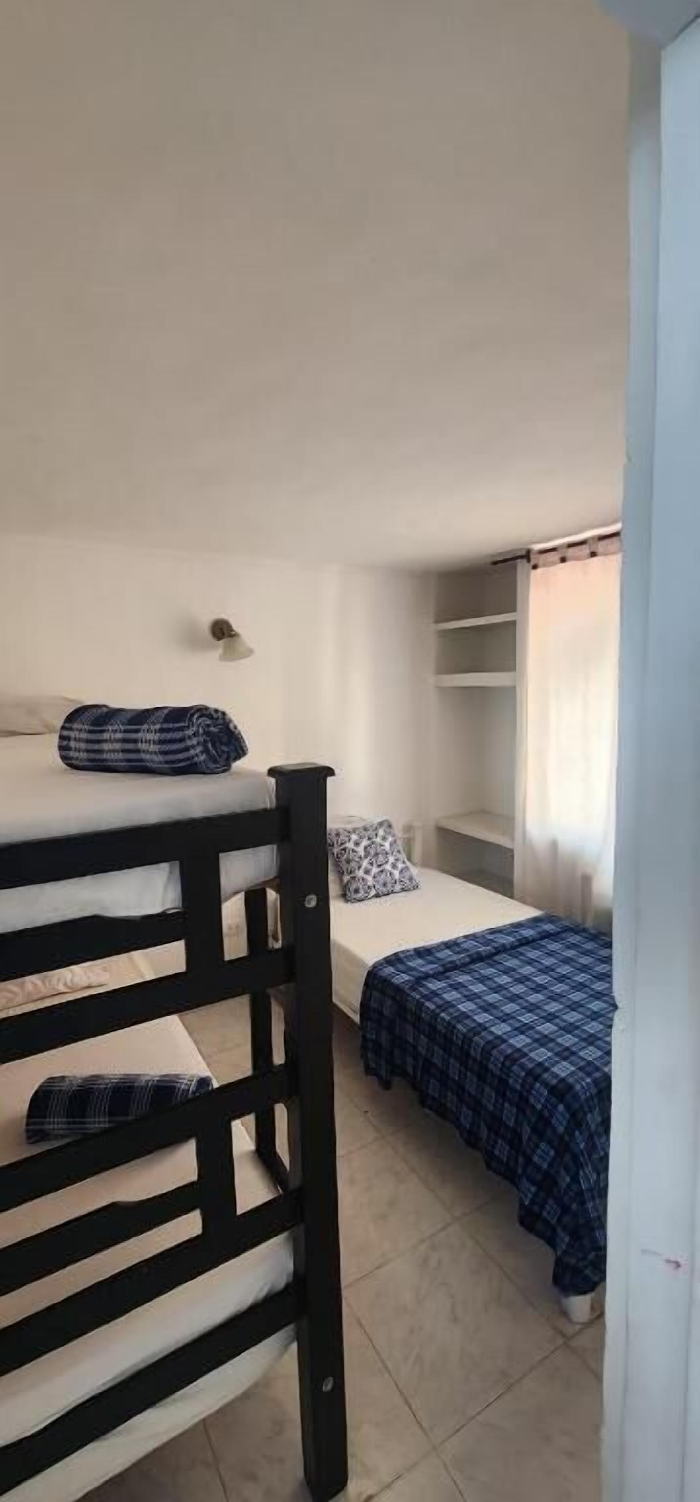 Ein Schlafsaalzimmer mit Etagenbetten, einem kleinen Schreibtisch und einem Fenster mit Vorhängen.