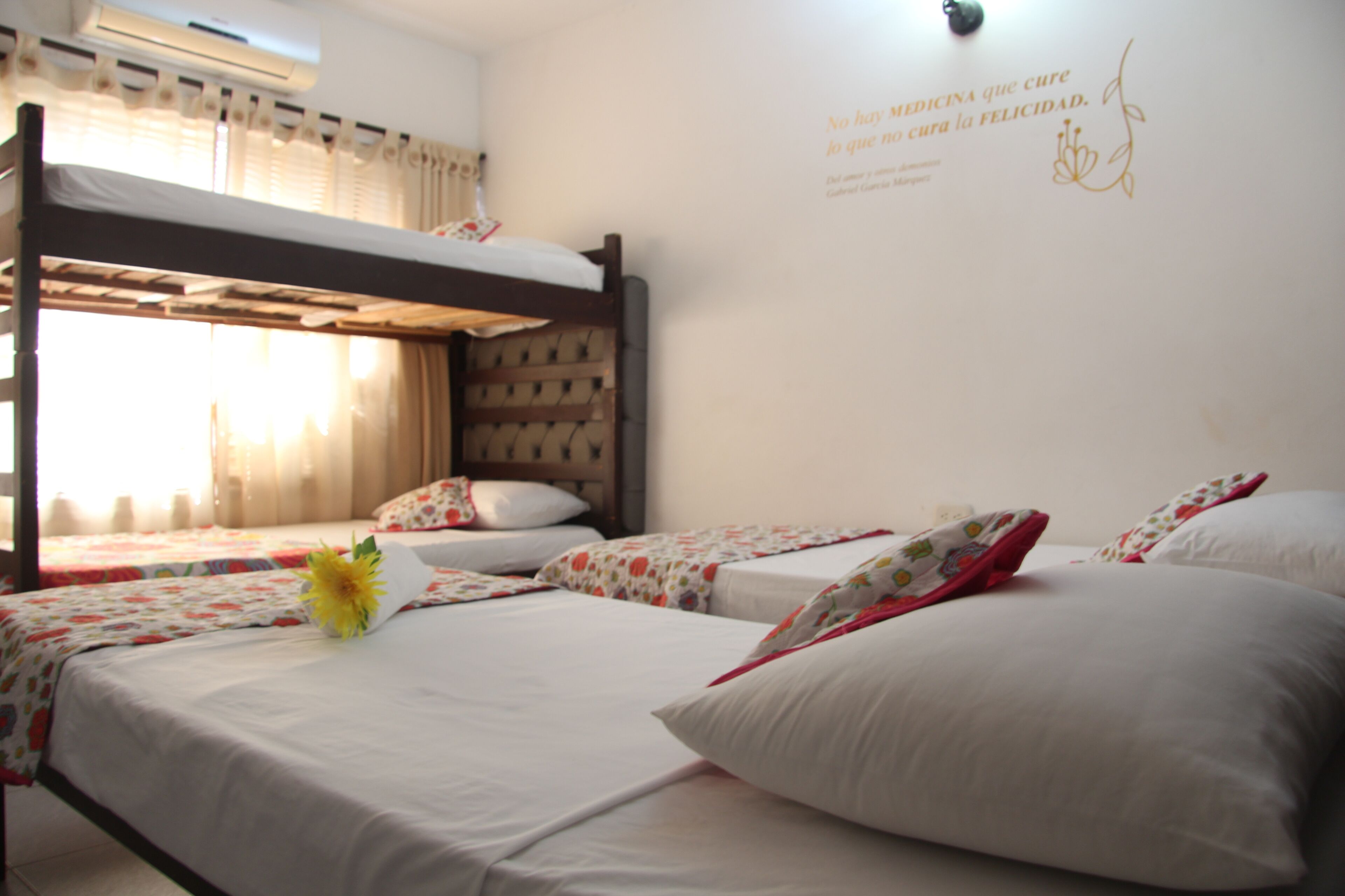 A hotel room with bunk beds, a floral bedspread, and a wall with a decorative quote.