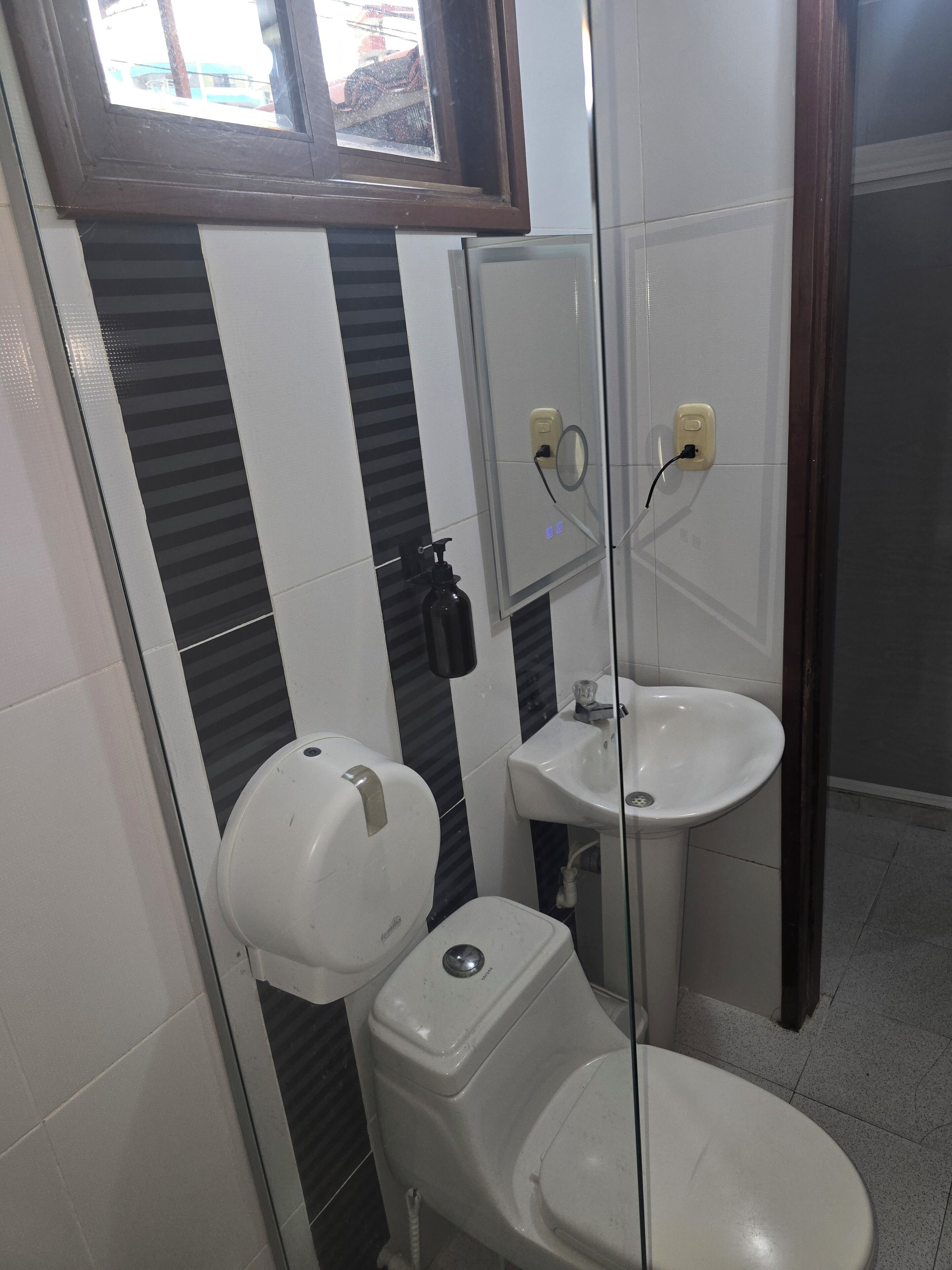 A bathroom with a toilet, a sink, and a mirror.