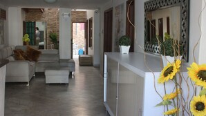 A modern living room with a sofa, a coffee table, and a cabinet. There is a mirror on the wall and a door leading to another room. - Hotel Rodadero Dorado (Santa Marta)