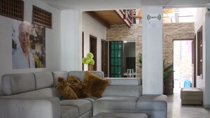 A spacious living area with a grey sectional sofa, a small ottoman, and a potted plant. - Hotel Rodadero Dorado (Santa Marta)