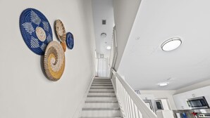 A staircase with a white railing leading to a kitchen area with modern appliances. - Sunflower Miami- A Family Retreat/ Fenced Turf Yard / BBQ-Free Parking (Miami)