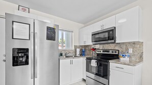 A modern kitchen with stainless steel appliances, white cabinets, and a granite countertop. - Sunflower Miami- A Family Retreat/ Fenced Turf Yard / BBQ-Free Parking (Miami)