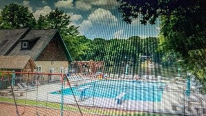 Un espace extérieur clos, doté d’une piscine, d’un petit bâtiment et d’arbres en arrière-plan.