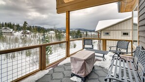 Ein überdachter Außenbereich mit Tisch und Stühlen, mit Blick auf eine verschneite Landschaft aus Häusern und Bäumen.