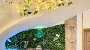 A cozy bedroom with a bed, a green wall, and string lights. - Nomadara - Boutique B&B (Coin)