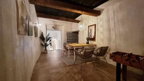A dining area with a wooden table and chairs, a hanging light fixture, and a foosball table. - Nomadara - Boutique B&B (Coin)