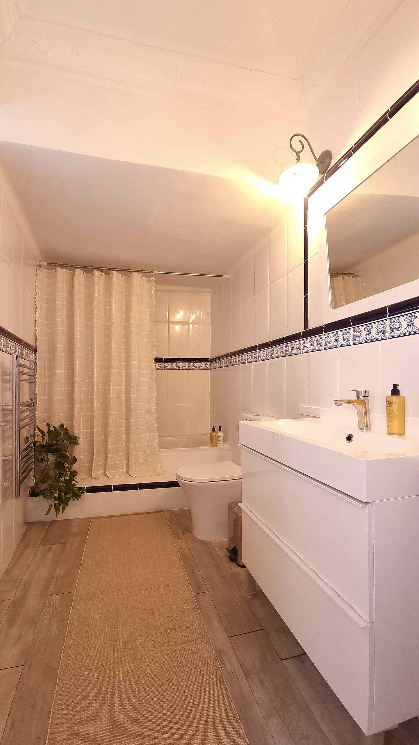 Une salle de bain avec un lavabo blanc, un miroir et un rideau de douche.