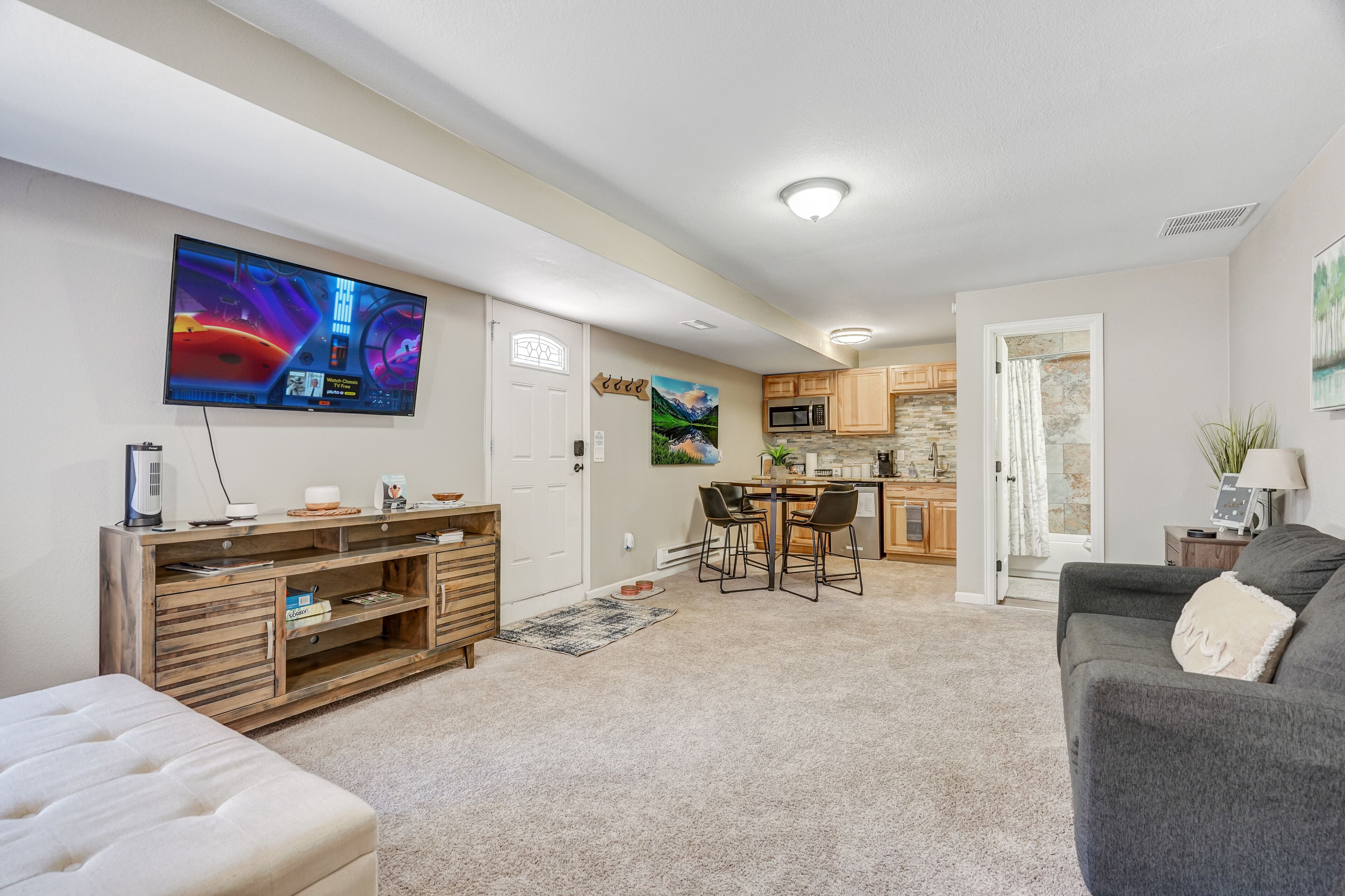 A modern living room with a flat-screen TV, wooden entertainment unit, and a grey sofa.
