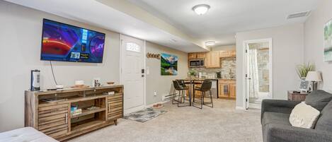 A modern living room with a flat-screen TV, wooden entertainment unit, and a grey sofa.