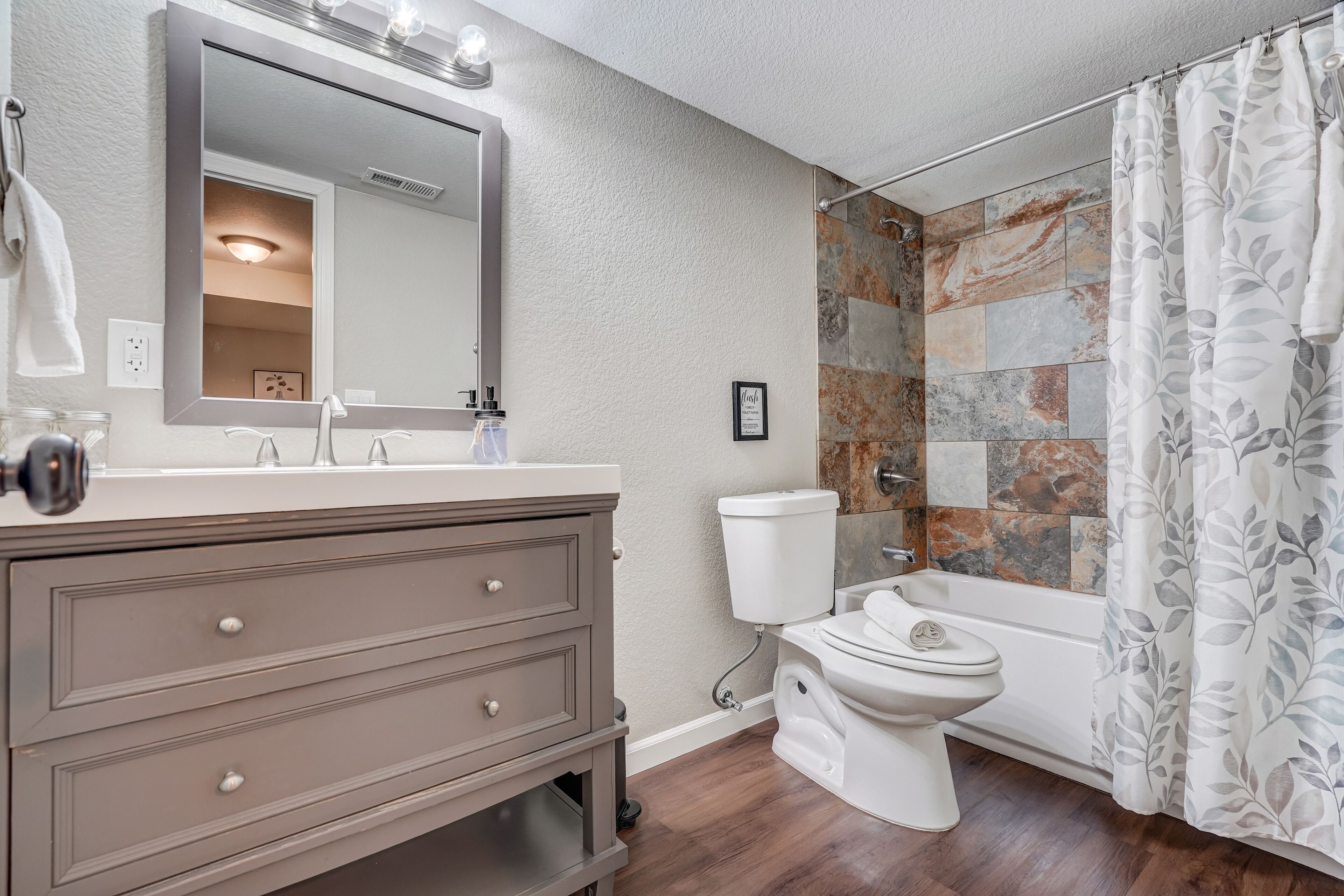A bathroom with a vanity, a toilet, and a shower area.