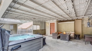 Un espace extérieur abrité comprenant un jacuzzi, des sièges et un foyer.