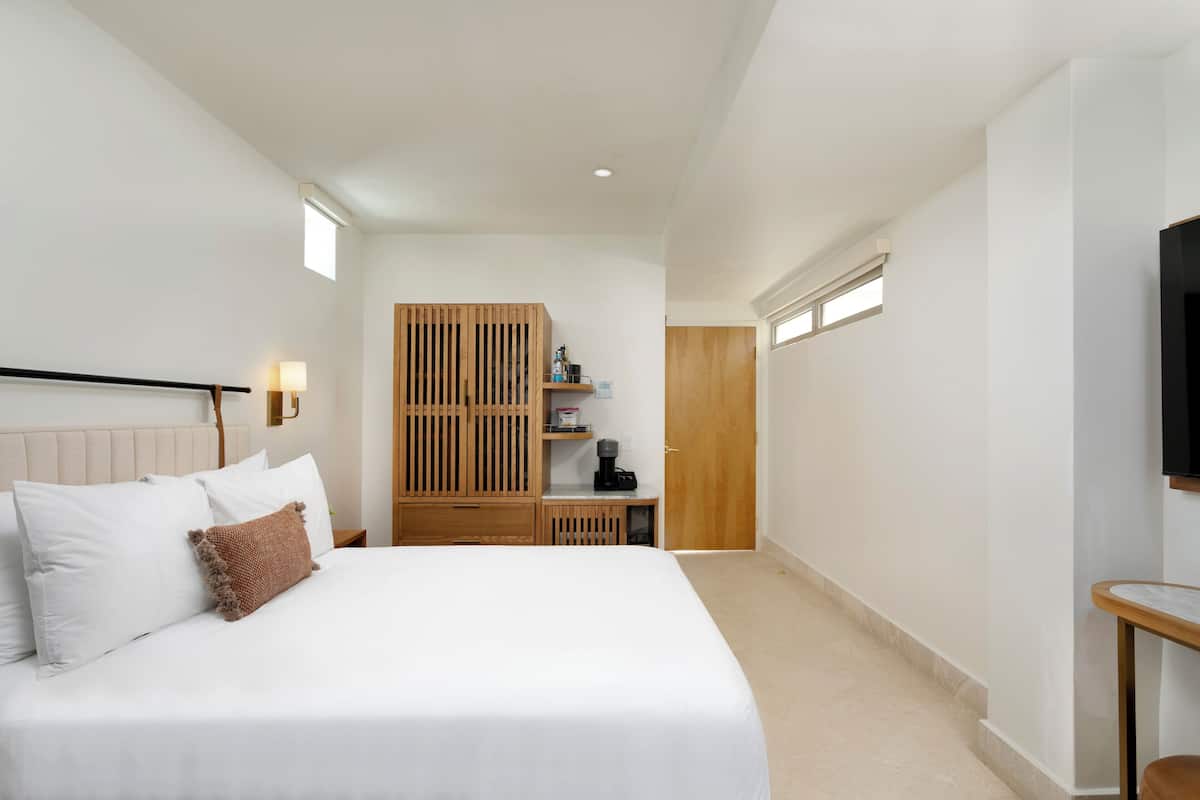 Ein Schlafzimmer mit einem großen Bett, einem Holzschrank, einem Nachttisch, einem Fernseher und einem kleinen Tisch.