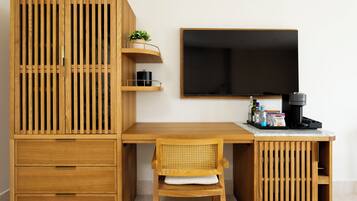 Una habitación moderna y minimalista con un escritorio de madera, una silla, un televisor y una cafetera.