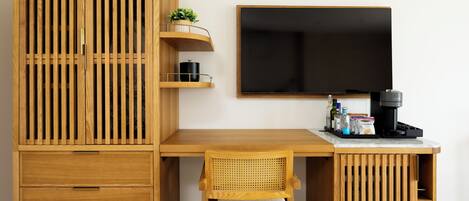 Una habitación moderna y minimalista con un escritorio de madera, una silla, un televisor y una cafetera.