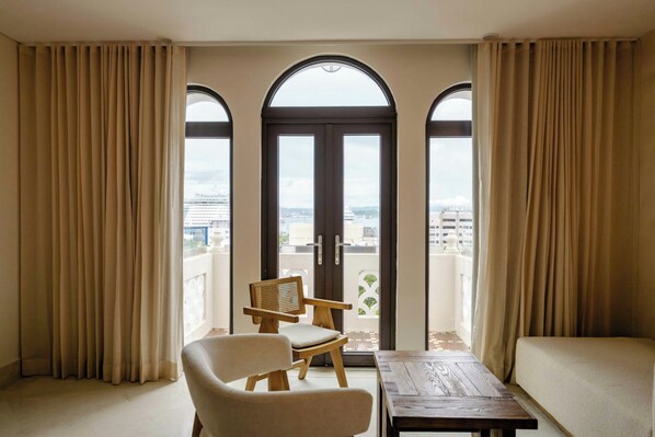 Un balcon avec vue sur la ville, une chaise en bois, un canapé et une table.